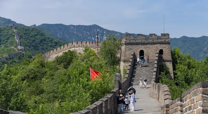 Marele Zid Chinezesc urcand pe creasta impadurita, cu turn de veghe